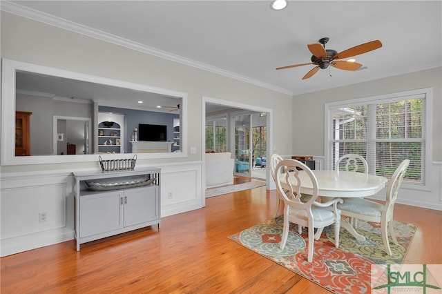 dining space with ceiling fan, light wood-type flooring, and crown molding