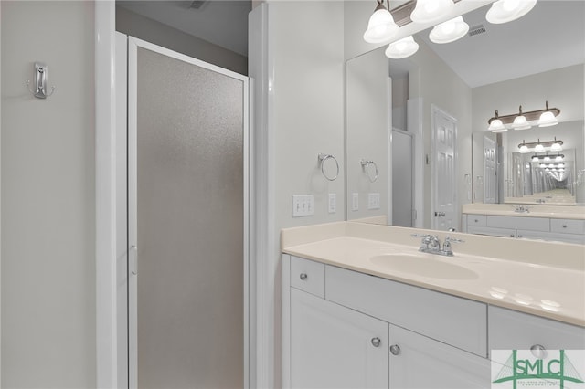 bathroom featuring a shower with door and vanity