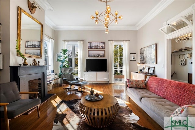 living room featuring hardwood / wood-style floors, ornamental molding, and an inviting chandelier