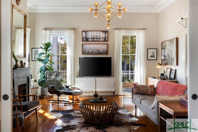 living room featuring an inviting chandelier, ornamental molding, and wood-type flooring