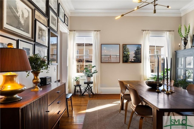 dining room featuring dark wood-type flooring, ornamental molding, and a chandelier