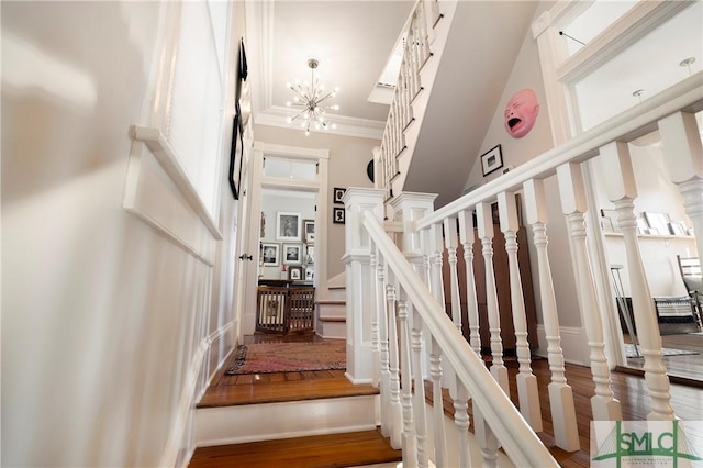 stairs with ornamental molding, a chandelier, and wood-type flooring