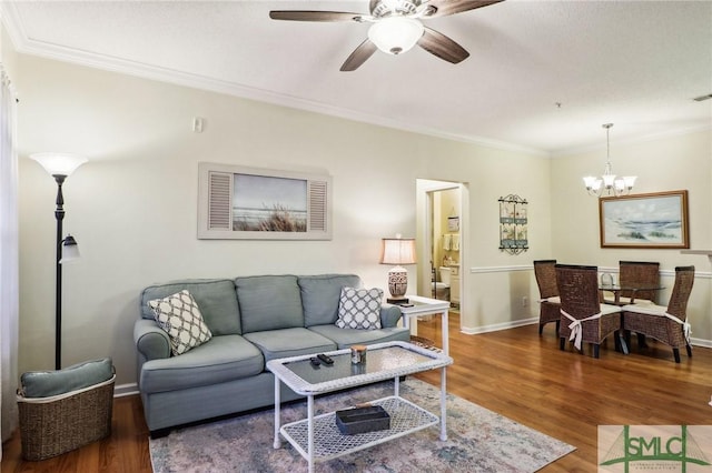 living room with crown molding, wood-type flooring, and ceiling fan with notable chandelier