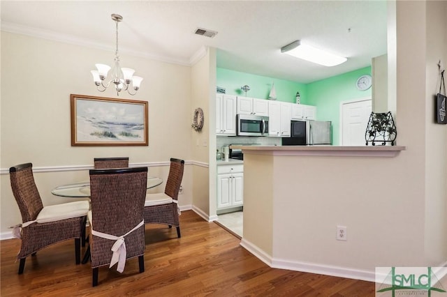 kitchen with white cabinetry, light hardwood / wood-style flooring, pendant lighting, and appliances with stainless steel finishes