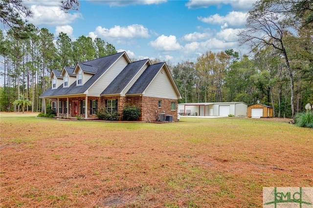 view of side of property with central AC unit, a garage, an outdoor structure, and a yard