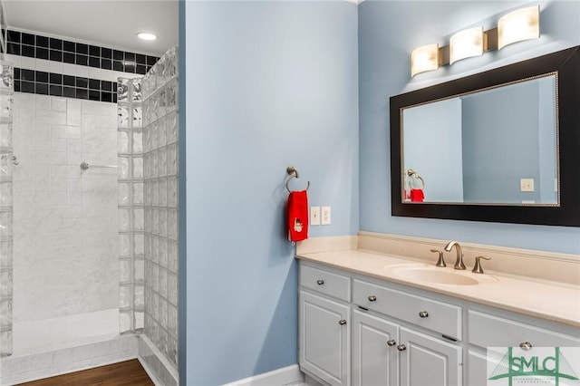 bathroom featuring tiled shower, hardwood / wood-style floors, and vanity