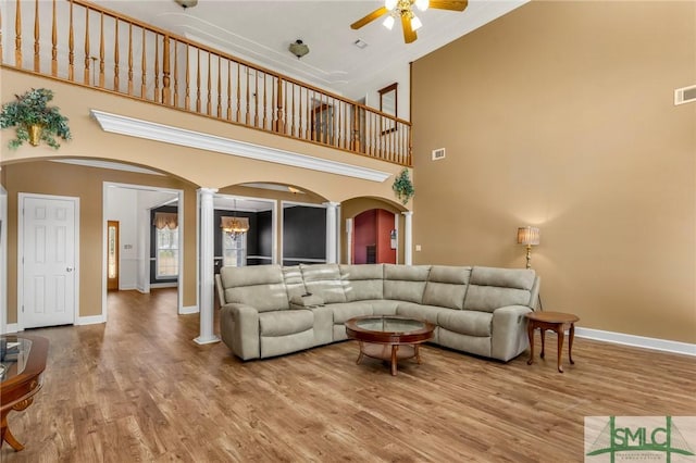 living room featuring hardwood / wood-style floors, a towering ceiling, decorative columns, and ceiling fan