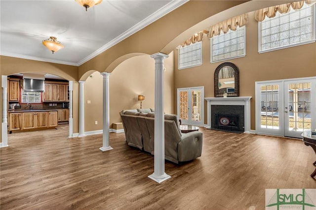 living room featuring french doors, light hardwood / wood-style flooring, ornate columns, and ornamental molding