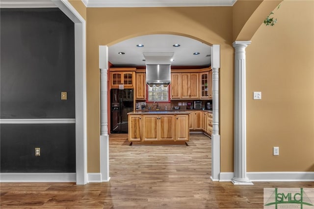 kitchen featuring ornate columns, wall chimney exhaust hood, light hardwood / wood-style flooring, black fridge with ice dispenser, and ornamental molding