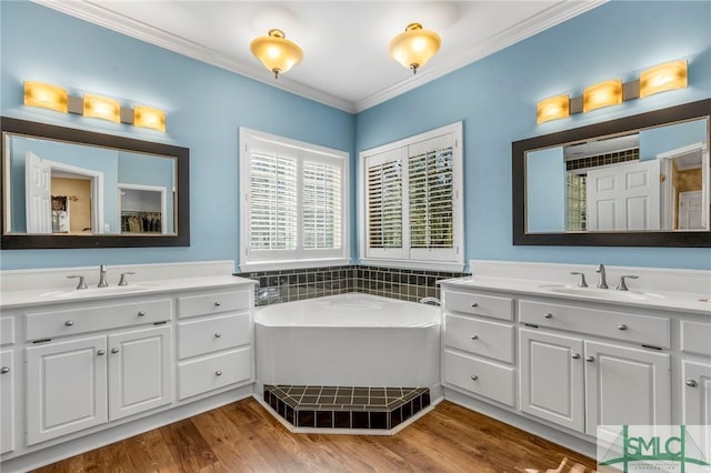 bathroom with a bath, vanity, hardwood / wood-style flooring, and crown molding