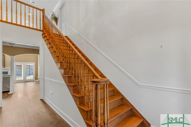 stairway with hardwood / wood-style flooring, french doors, and decorative columns