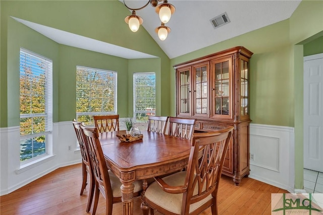 dining area featuring a chandelier, vaulted ceiling, and light hardwood / wood-style flooring