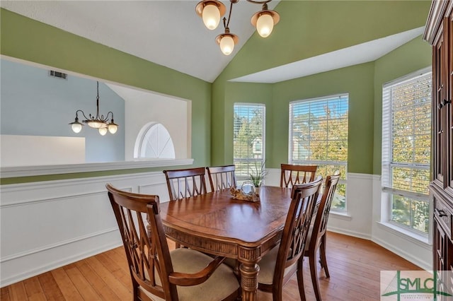 dining area featuring a chandelier, light wood-type flooring, lofted ceiling, and a healthy amount of sunlight