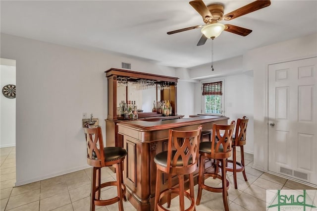 dining room featuring ceiling fan, light tile patterned floors, and bar