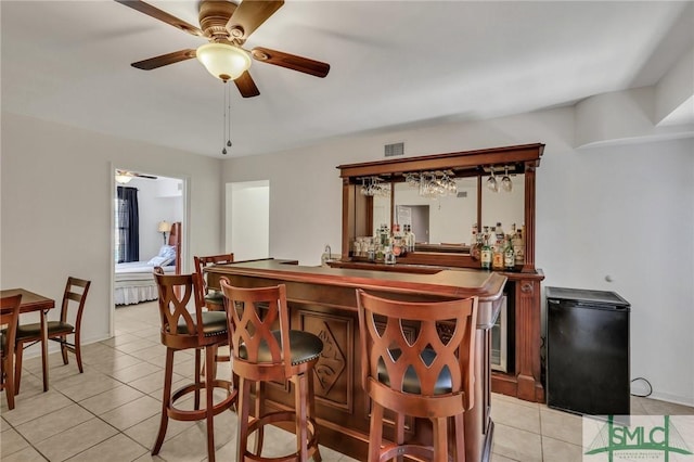 bar featuring black fridge, ceiling fan, and light tile patterned flooring