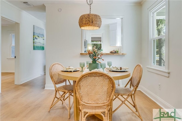 dining area featuring light wood-type flooring and crown molding