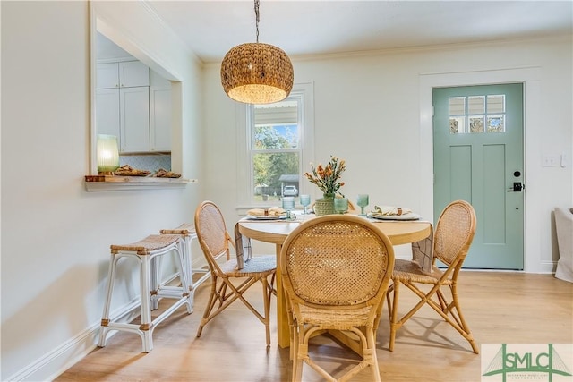 dining area featuring light wood-type flooring and ornamental molding