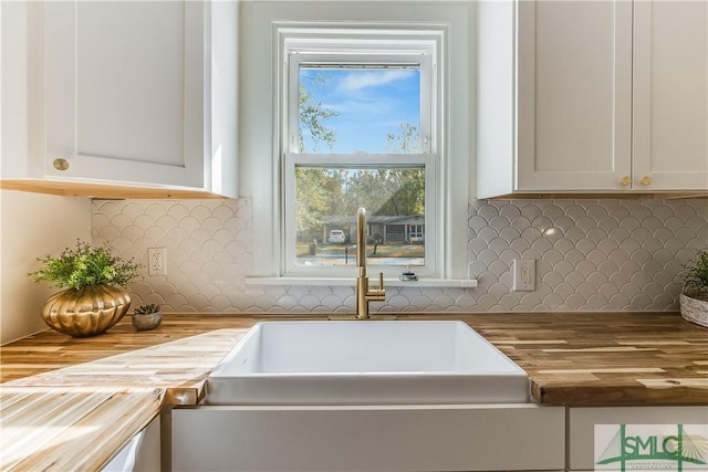 room details with white cabinetry, butcher block counters, tasteful backsplash, and sink