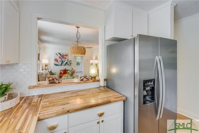 kitchen with butcher block counters, stainless steel fridge, decorative backsplash, pendant lighting, and white cabinets