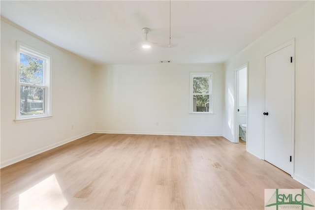 unfurnished room featuring light wood-type flooring, a wealth of natural light, and crown molding