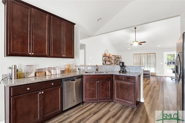 kitchen with lofted ceiling, sink, light wood-type flooring, appliances with stainless steel finishes, and light stone counters