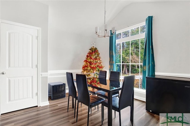 dining space featuring hardwood / wood-style floors, lofted ceiling, and a notable chandelier