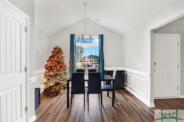 dining room with hardwood / wood-style floors, an inviting chandelier, and lofted ceiling