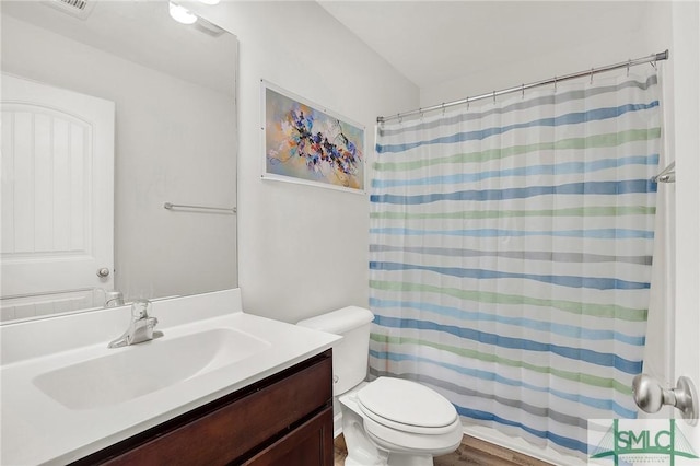 bathroom featuring walk in shower, hardwood / wood-style flooring, vanity, and toilet