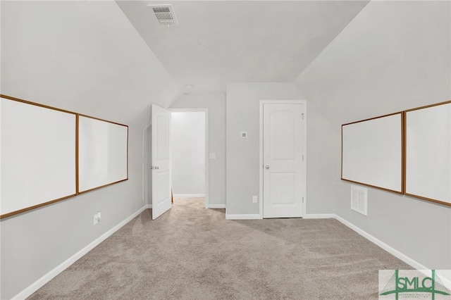 additional living space featuring light colored carpet and vaulted ceiling