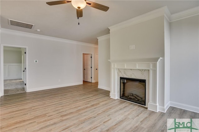 unfurnished living room featuring a high end fireplace, light hardwood / wood-style floors, ceiling fan, and ornamental molding