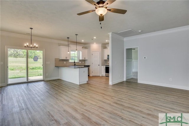 kitchen featuring a wealth of natural light, white cabinets, decorative light fixtures, and light wood-type flooring