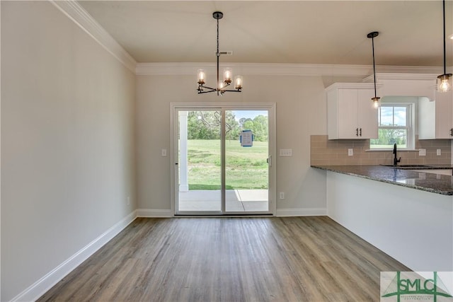 kitchen with white cabinetry, dark stone counters, decorative light fixtures, decorative backsplash, and light wood-type flooring