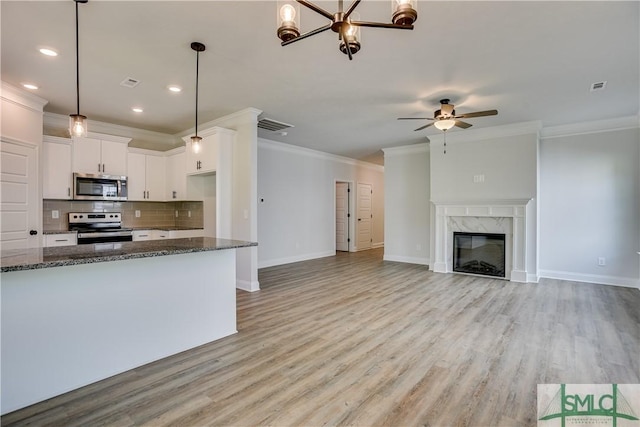 kitchen with white cabinets, dark stone countertops, stainless steel appliances, and light hardwood / wood-style flooring