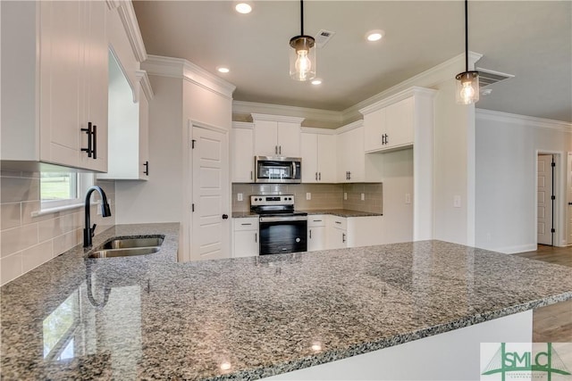 kitchen featuring kitchen peninsula, appliances with stainless steel finishes, dark stone countertops, white cabinets, and hardwood / wood-style floors