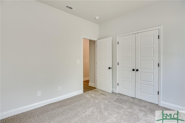 unfurnished bedroom with light carpet and a closet