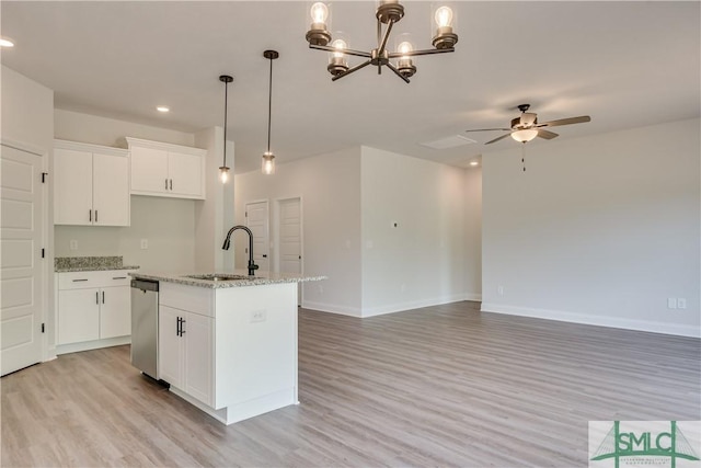 kitchen featuring light stone countertops, stainless steel dishwasher, sink, white cabinetry, and an island with sink