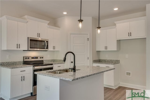 kitchen featuring light stone countertops, stainless steel appliances, white cabinetry, and an island with sink