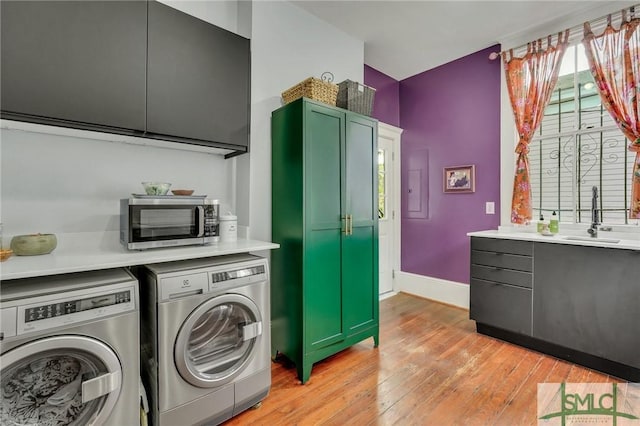 clothes washing area featuring separate washer and dryer, sink, cabinets, and light wood-type flooring