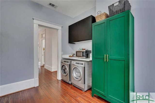 laundry room with independent washer and dryer, cabinets, and light wood-type flooring