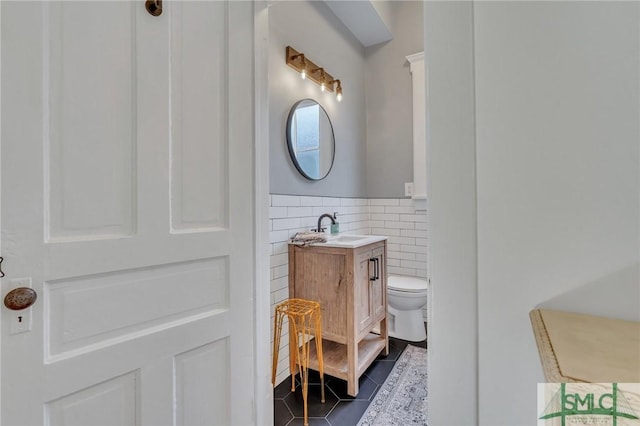 bathroom with tile patterned floors, vanity, tile walls, and toilet