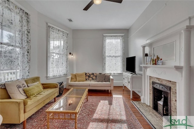 living room featuring ceiling fan, wood-type flooring, a wealth of natural light, and a premium fireplace