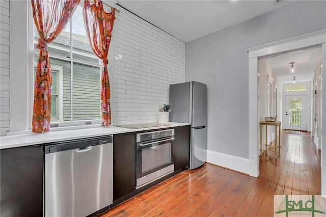 kitchen featuring appliances with stainless steel finishes, backsplash, and wood-type flooring