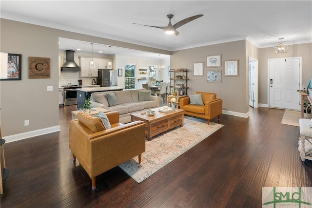 living room with ceiling fan with notable chandelier, ornamental molding, and dark wood-type flooring