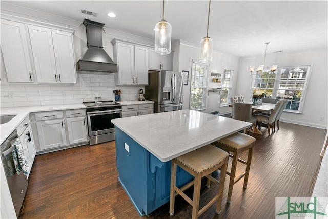 kitchen with custom exhaust hood, a center island, white cabinets, hanging light fixtures, and appliances with stainless steel finishes