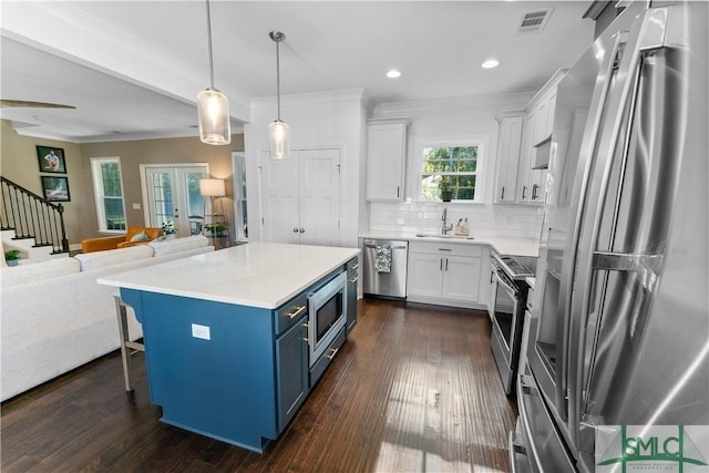 kitchen with a center island, white cabinets, dark hardwood / wood-style floors, blue cabinetry, and stainless steel appliances