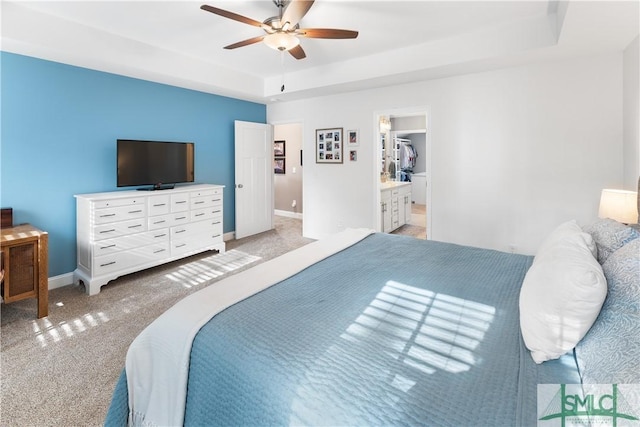 carpeted bedroom with a spacious closet, a raised ceiling, and ceiling fan