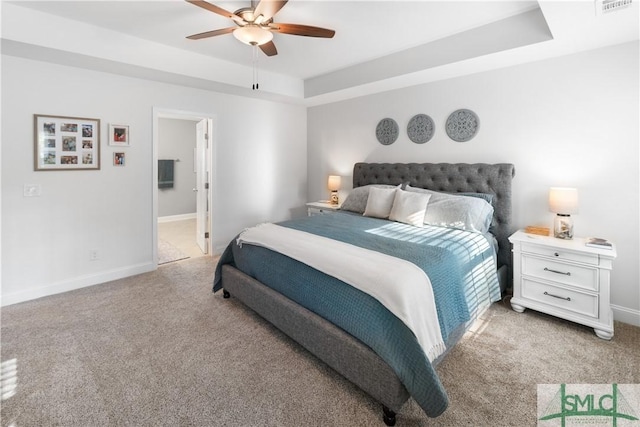 carpeted bedroom featuring ensuite bathroom, ceiling fan, and a raised ceiling