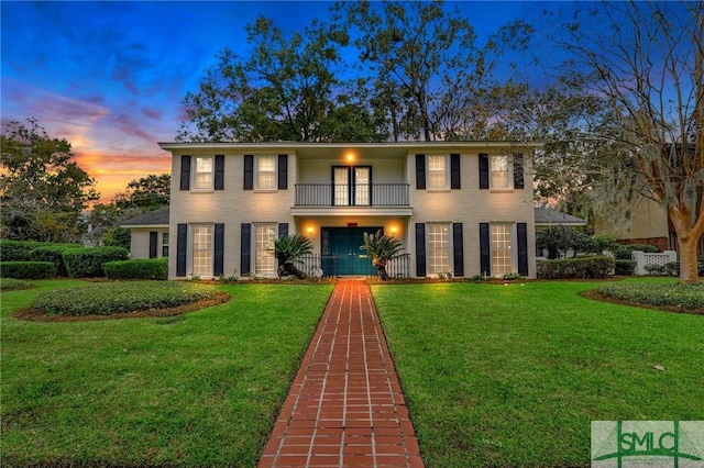 view of front of property featuring a balcony and a lawn