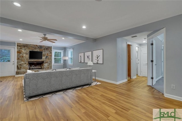 living room featuring a fireplace, light wood-type flooring, and ceiling fan