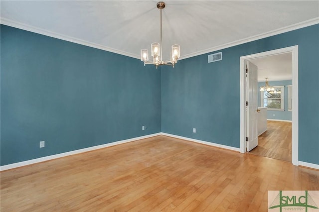 empty room featuring hardwood / wood-style flooring, a notable chandelier, and ornamental molding